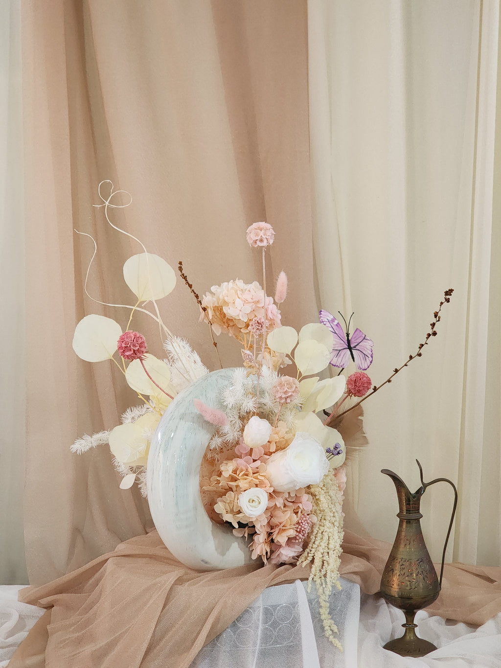 Side view of donut vase floral arrangement with butterfly accent