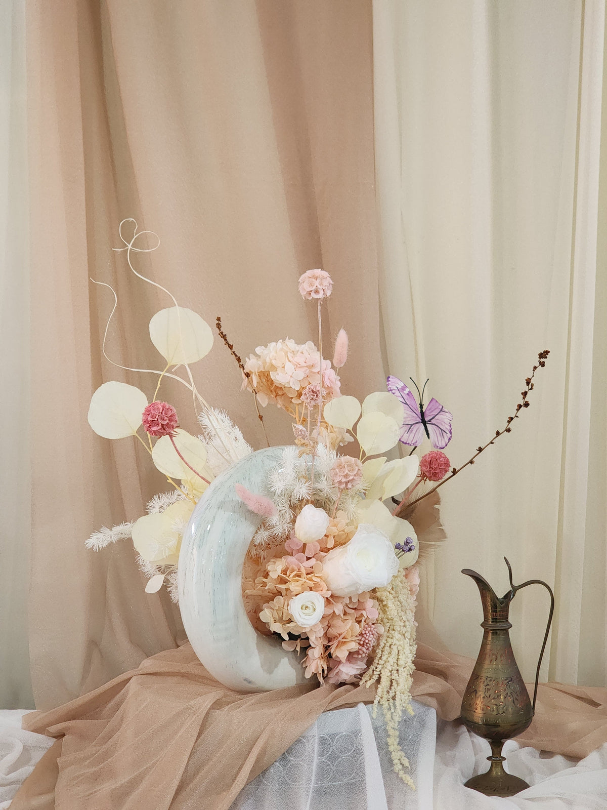 Side view of donut vase floral arrangement with butterfly accent