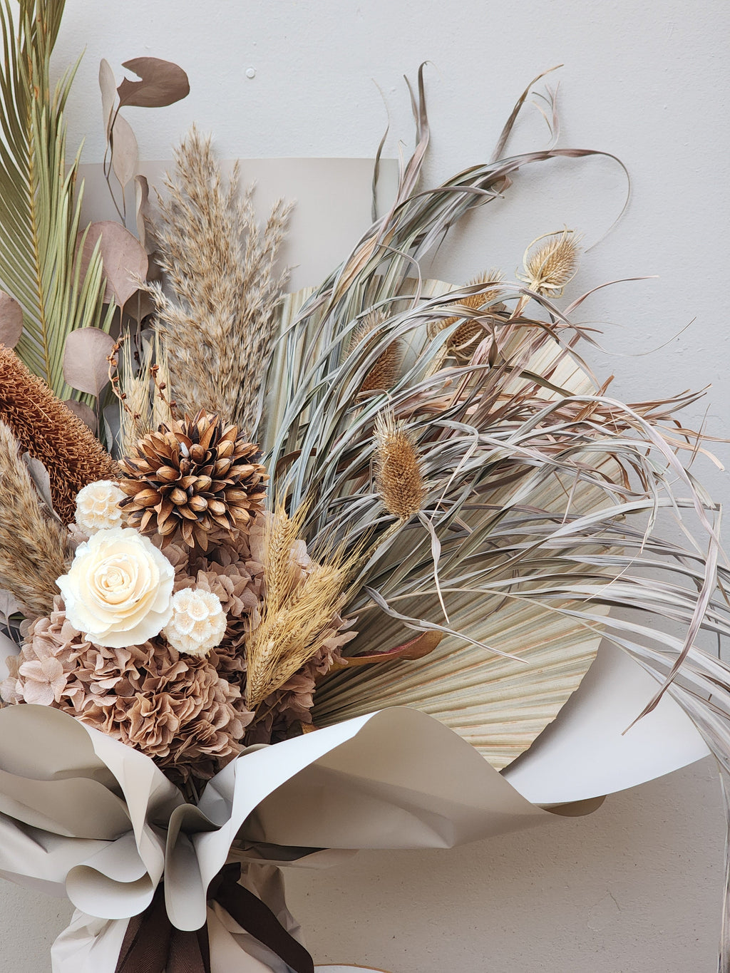 Detail shot of boho dried bouquet with teasel and palm leaves